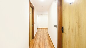 A hallway with wooden doors, a light-colored floor, and a ceiling with recessed lighting. - Fabhotel Sky Inn (New Delhi)
