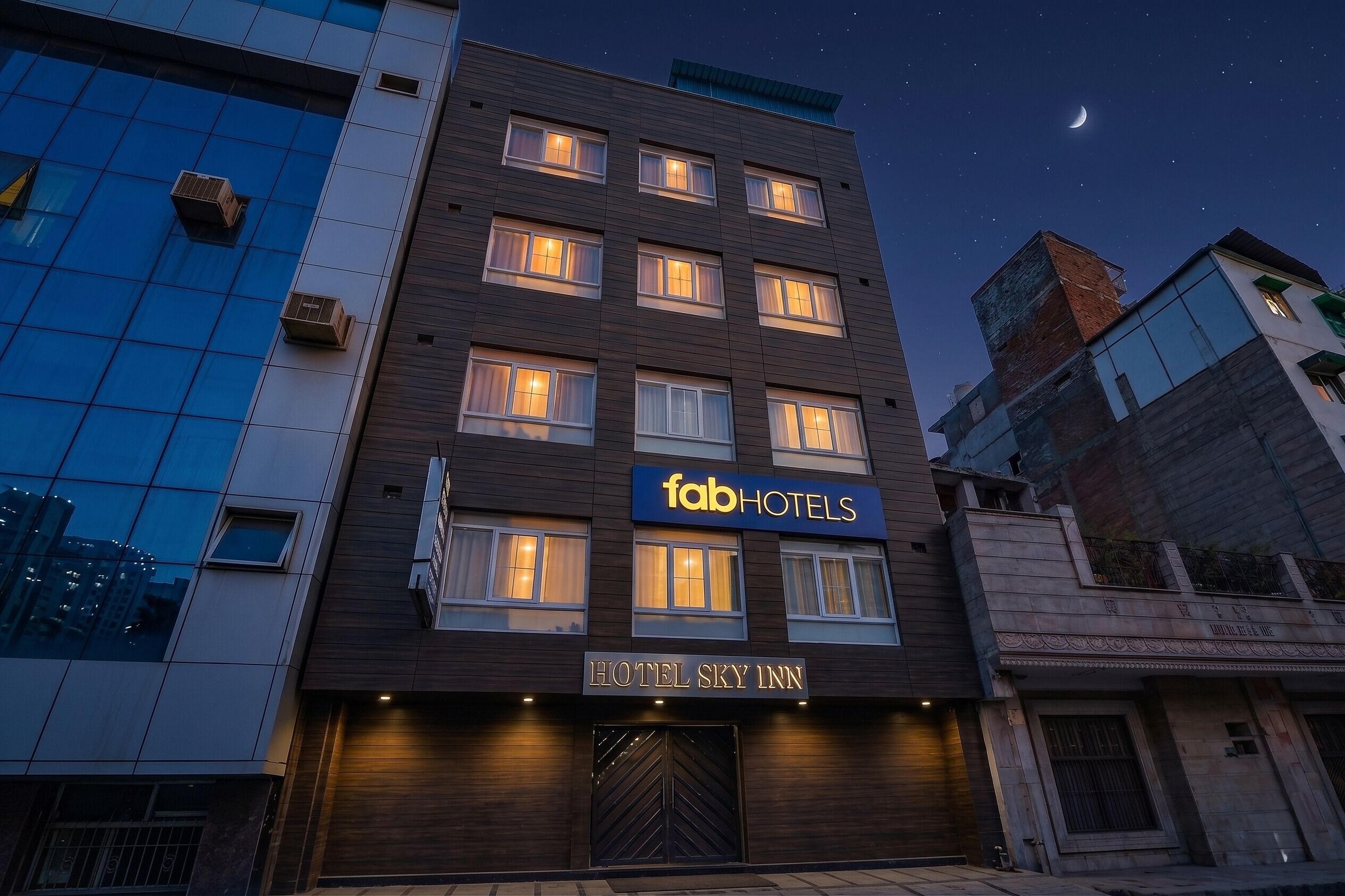 A multi-story building with a 'fabHOTELS' sign, 'HOTEL SKY INN' signage, and a visible entrance with a modern design.