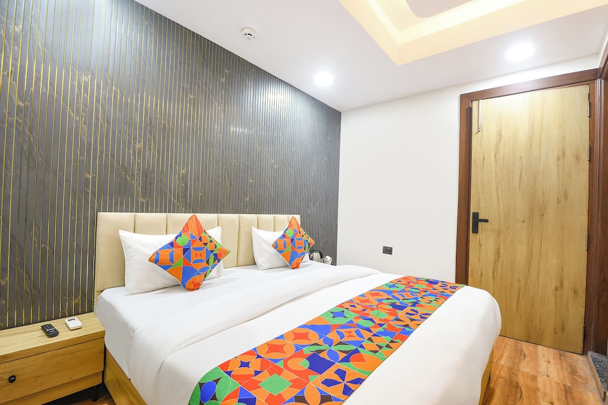A modern bedroom with a bed, pillows, a wooden door, and a nightstand.