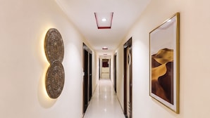 Un pasillo de hotel con diseño moderno, que presenta un largo corredor, iluminación decorativa en la pared y obras de arte enmarcadas.