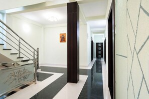 Un pasillo moderno de hotel con una escalera, un pilar de madera oscura y un cuadro en la pared.