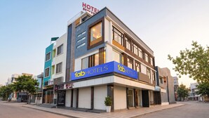 Un hotel moderno con un llamativo letrero de 'fabHOTELS', un letrero en la azotea que dice 'HOTEL SKYVIEW', y una entrada visible con un toldo cerrado.
