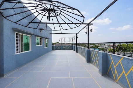 A rooftop terrace with a blue textured wall, yellow diamond patterns, and a metal umbrella structure.. Fabhotel Skyview