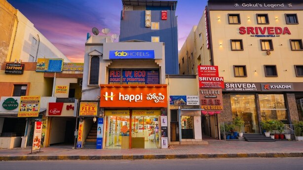 A hotel named 'fabHOTELS' with a signboard for 'happi world' and 'flex' printing services.