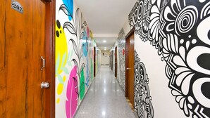 A hallway with wooden doors, colorful wall art, and a polished floor.