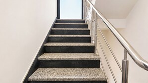 Una escalera con barandilla de metal y peldaños oscuros.