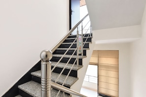 A modern staircase with a metal handrail and a glass door at the top.