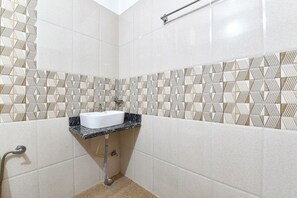 A bathroom with a white sink, patterned tiles, and a shower area.