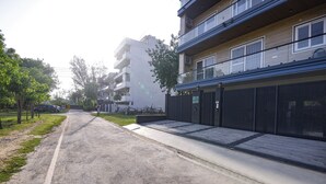 A residential street with apartment buildings, a gated entrance, and a clear road. - Fabhotel The Mamta Grande (Gurugram)