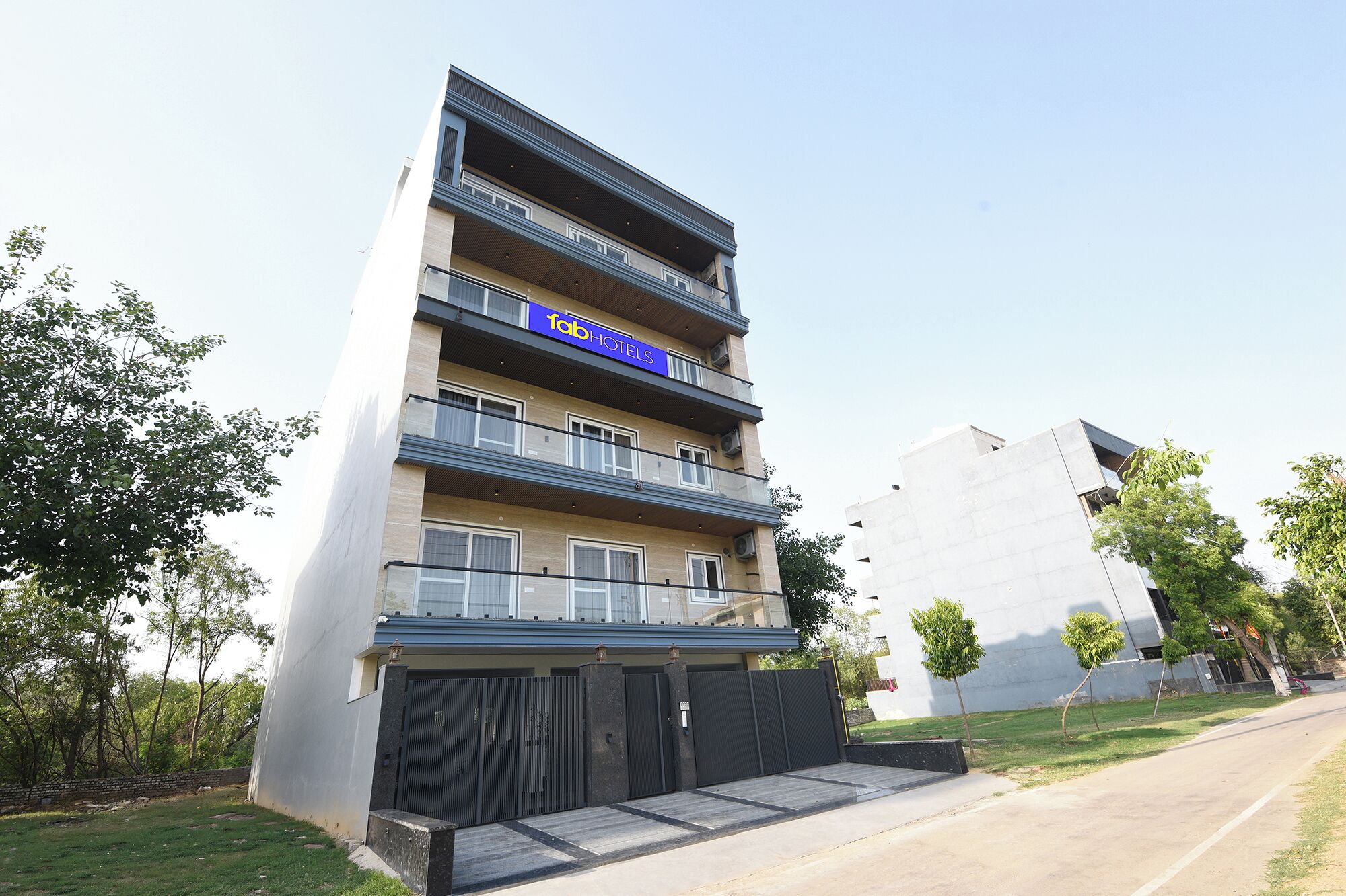 A multi-story hotel with balconies, a gated entrance, and a clear sky.