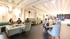 Un comedor moderno con mesas, sillas, una barra y una zona de estar con vistas a la cocina.