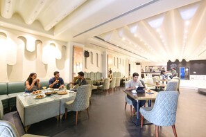 Un comedor moderno con mesas, sillas, una barra y una zona de estar con vistas a la cocina.