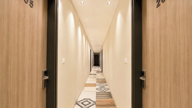 A hotel hallway with wooden doors numbered 205 and 209, leading to a room. - FabHotel The Rolex Grand - Yatharth Super Speciality Hospital, Sector 20 (Faridabad)