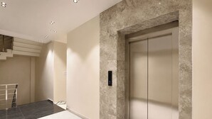 A modern elevator with a marble wall, a control panel, and a staircase with metal railings. - FabHotel The Rolex Grand - Yatharth Super Speciality Hospital, Sector 20 (Faridabad)