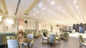 A modern restaurant with a mix of seating options including booths and tables, a bar area, and a visible kitchen. - FabHotel The Rolex Grand - Yatharth Super Speciality Hospital, Sector 20 (Faridabad)