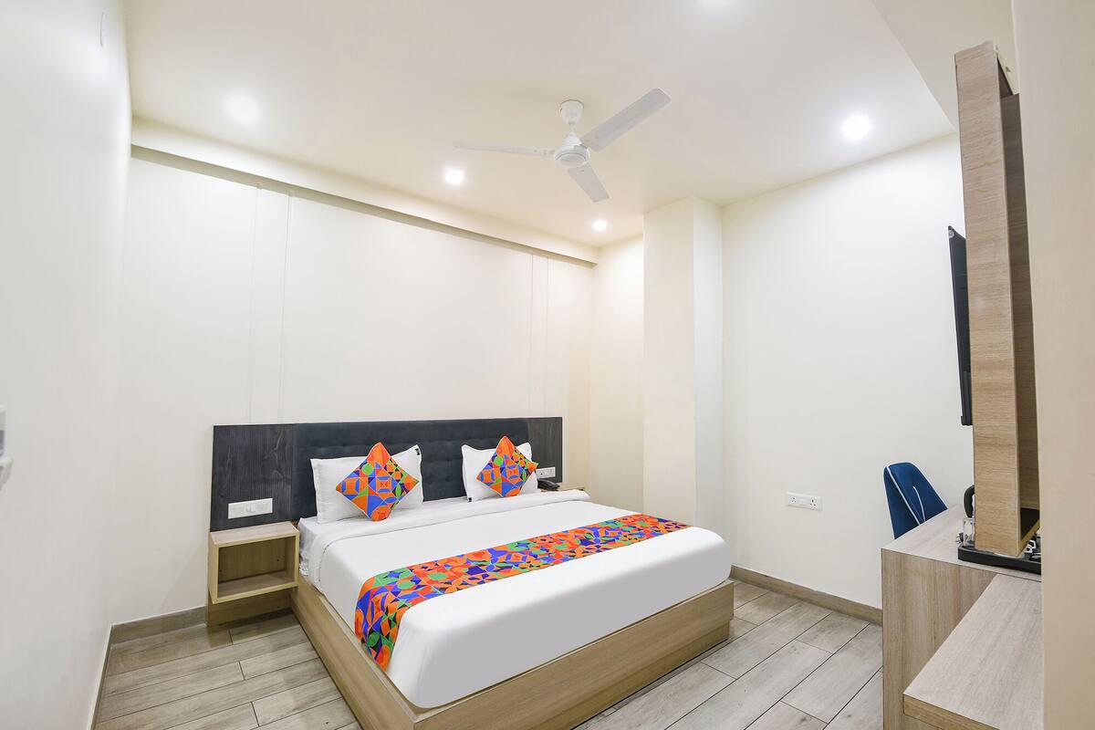 Un dormitorio moderno con una cama, un ventilador de techo, una mesita de noche y un escritorio con una silla.