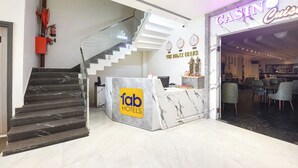 A hotel lobby with a marble reception desk, a staircase, and a casino sign. - FabHotel The Rolex Grand - Yatharth Super Speciality Hospital, Sector 20 (Faridabad)