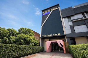 A modern building with a sign for 'The Rolex Grand Hotel' and 'Faber Hotels.' - Fabhotel The Rolex Grand (Faridabad)