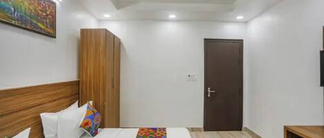 A hotel room with a bed, a wardrobe, a door, and a ceiling fan.