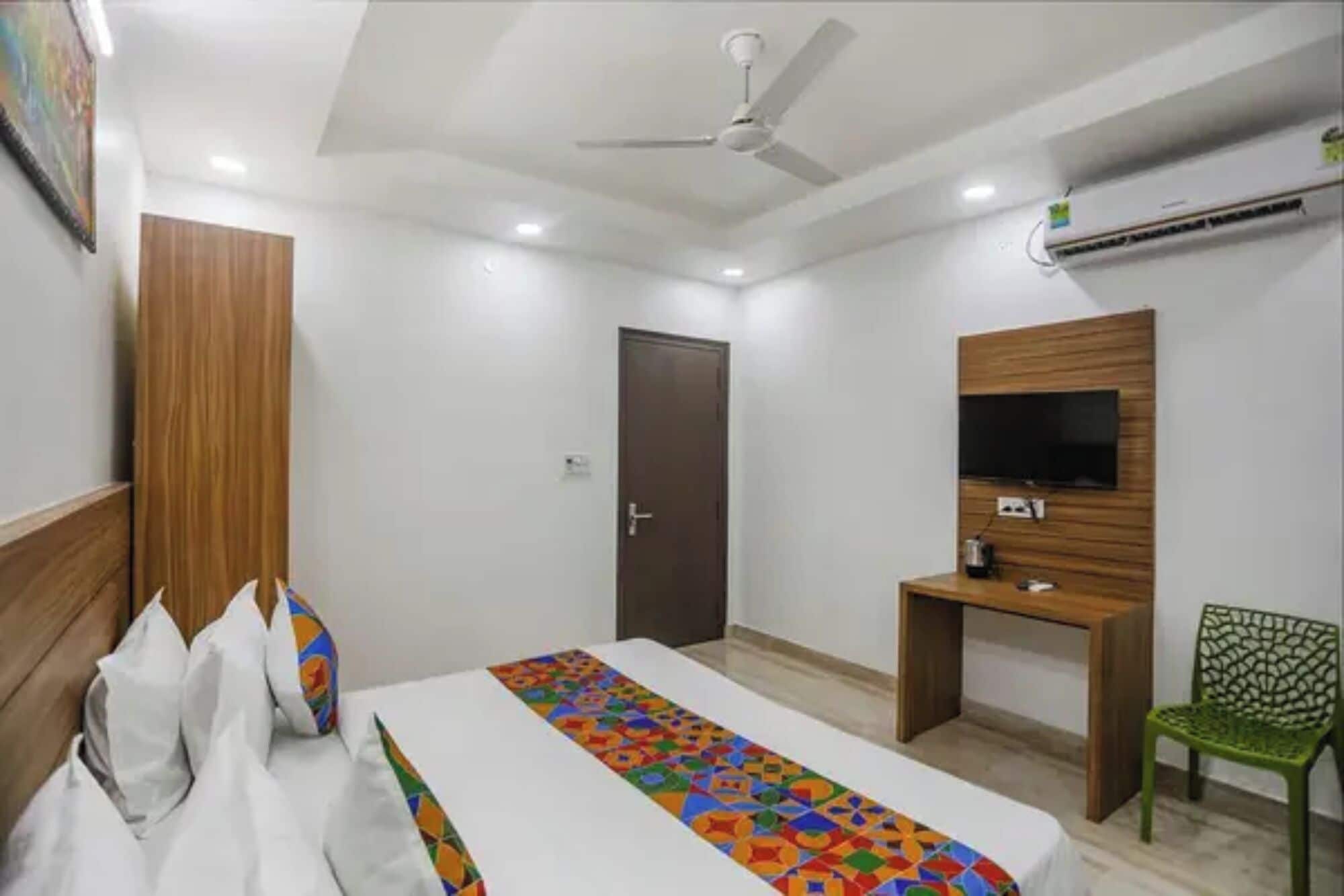 A hotel room with a bed, a desk, a TV, a chair, and a ceiling fan.