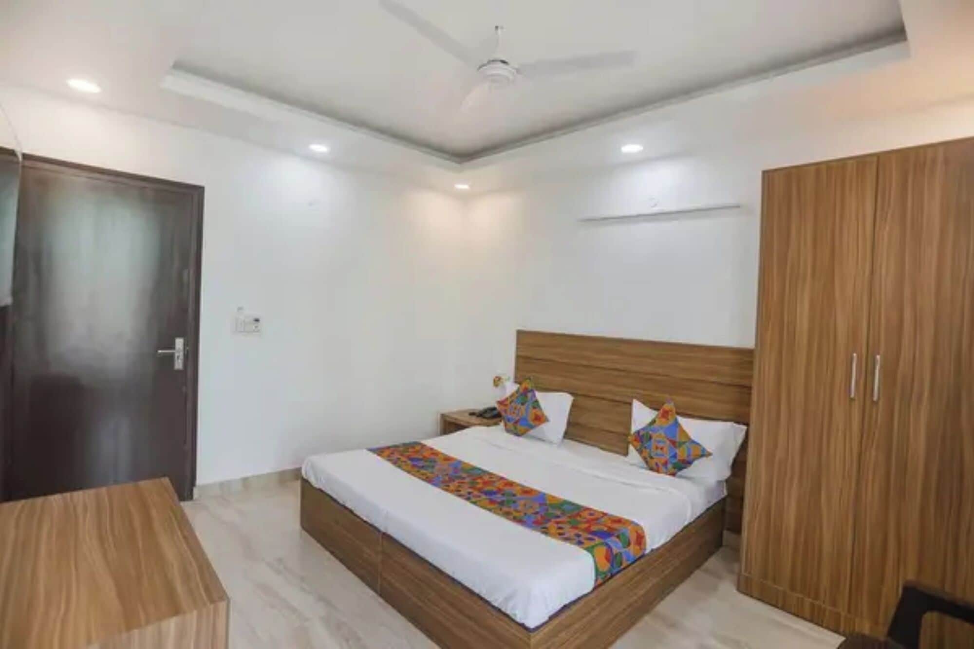 Un dormitorio con cama, armario de madera y ventilador de techo.
