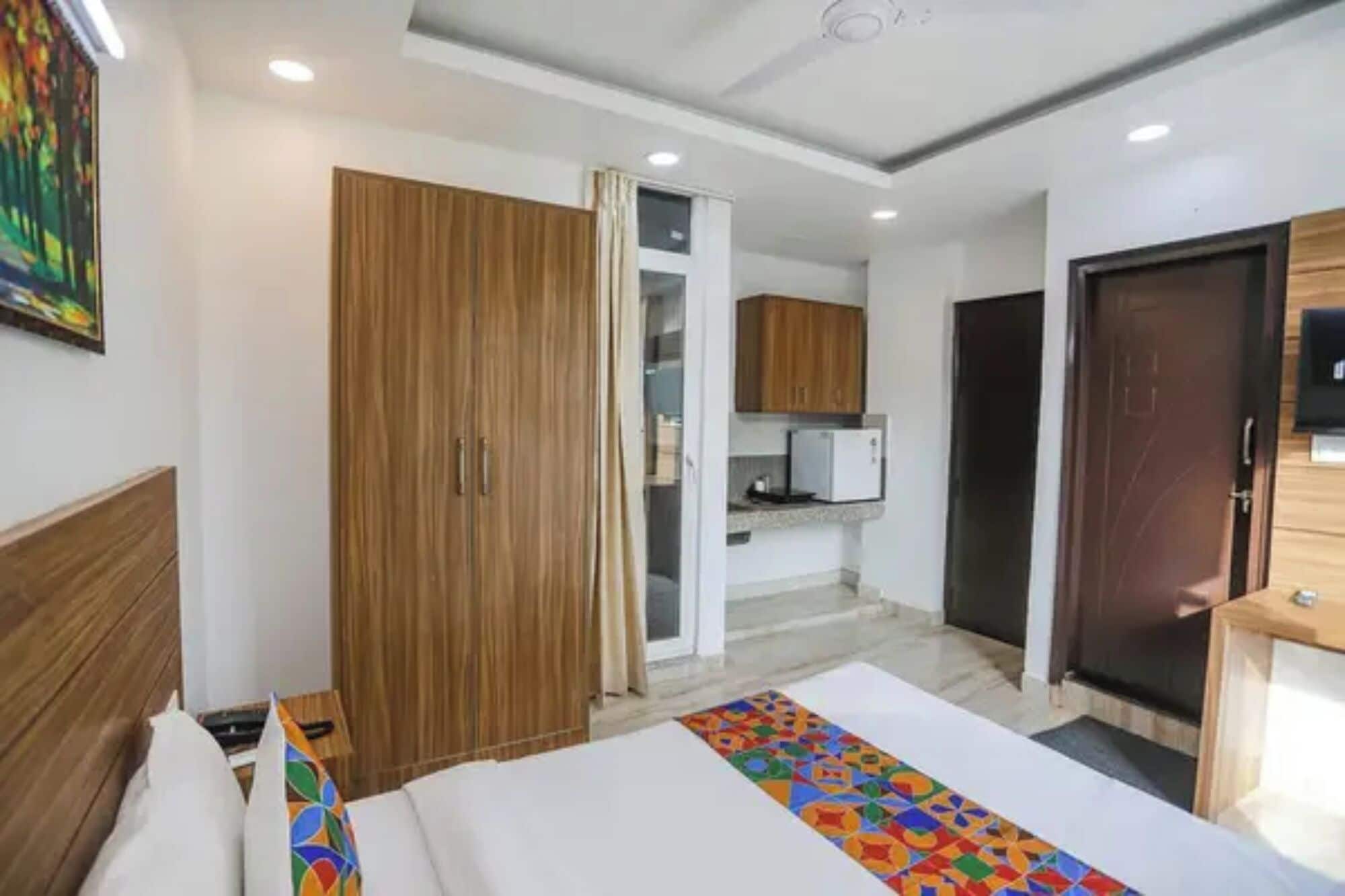 A bedroom with a bed, a wardrobe, a door, and a small kitchenette.