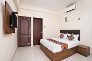 A bedroom with a bed, bedside tables, an air conditioner, a wardrobe, and a TV.