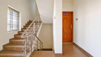 Una escalera con barandillas de metal, una puerta de madera y un ventanal con rejas.
