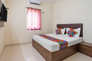 A bedroom with a bed, a window with curtains, an air conditioning unit, and a television. - Fabhotel V Inn Rooms (Chennai)