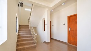 Una escalera con barandilla, una puerta de madera y un aplique en la pared.