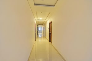 Um corredor longo e bem iluminado, com portas em ambos os lados que dão para os quartos.