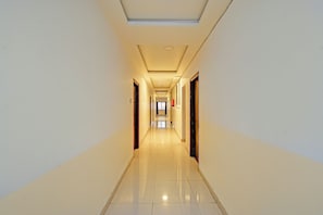 A long, narrow hotel corridor with doors on both sides, a tiled floor, and a ceiling with recessed lighting. - Fabhotel White Ridge Kamineni (Hyderabad)