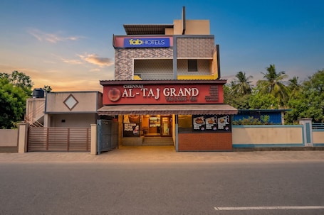 A multi-story building with a sign for 'fabHOTELS' and 'AL-TAJ GRAND' with a view of the sky and palm trees.. Fabhotel Whites Inn Vandalur