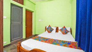 A room with a bed, a wooden wardrobe, and a blue curtain. - Fabhotel Whites Inn Vandalur (Chengalpattu)