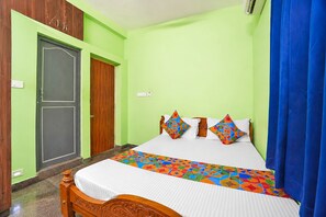 A room with a bed, a wooden wardrobe, and a blue curtain. - Fabhotel Whites Inn Vandalur (Chengalpattu)