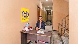 A hotel reception desk with a laptop, books, and a pen holder. - Fabhotel Whites Inn Vandalur (Chengalpattu)