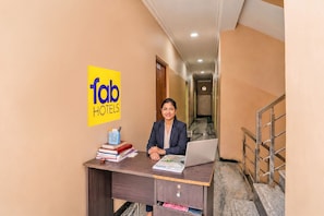 A hotel reception desk with a laptop, books, and a pen holder.