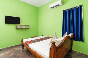 A room with a bed, a wall-mounted air conditioner, a television, and a window with curtains.