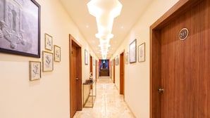 A hotel hallway with framed botanical prints, wooden doors, and a central staircase. - FabHotel Zamzam Residency (Bhopal)
