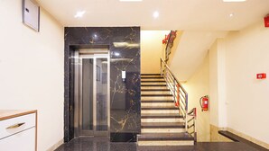 A modern interior with a marble staircase, a fire extinguisher, and a door leading to an elevator. - FabHotel Zamzam Residency (Bhopal)