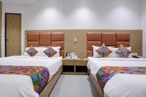 A hotel room with two beds, a nightstand, and a wall-mounted control panel.