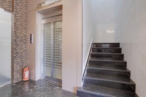 A hotel lobby with a marble staircase, a fire extinguisher, and a glass elevator. - Fabhotel Zillion Executive (Mumbai)