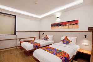 A hotel room with two beds, a desk, and a painting on the wall.