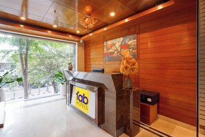 A hotel reception desk with a marble counter, a wooden wall, and a large window.