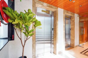 A modern elevator with a 'Guest Lift' sign, a potted plant, and a 'Service Lift' sign.
