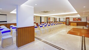A conference room with rows of chairs, a wooden panel wall, and a marble floor. - Fabhotel the prime Briklane -BTM Layout (Bangalore)