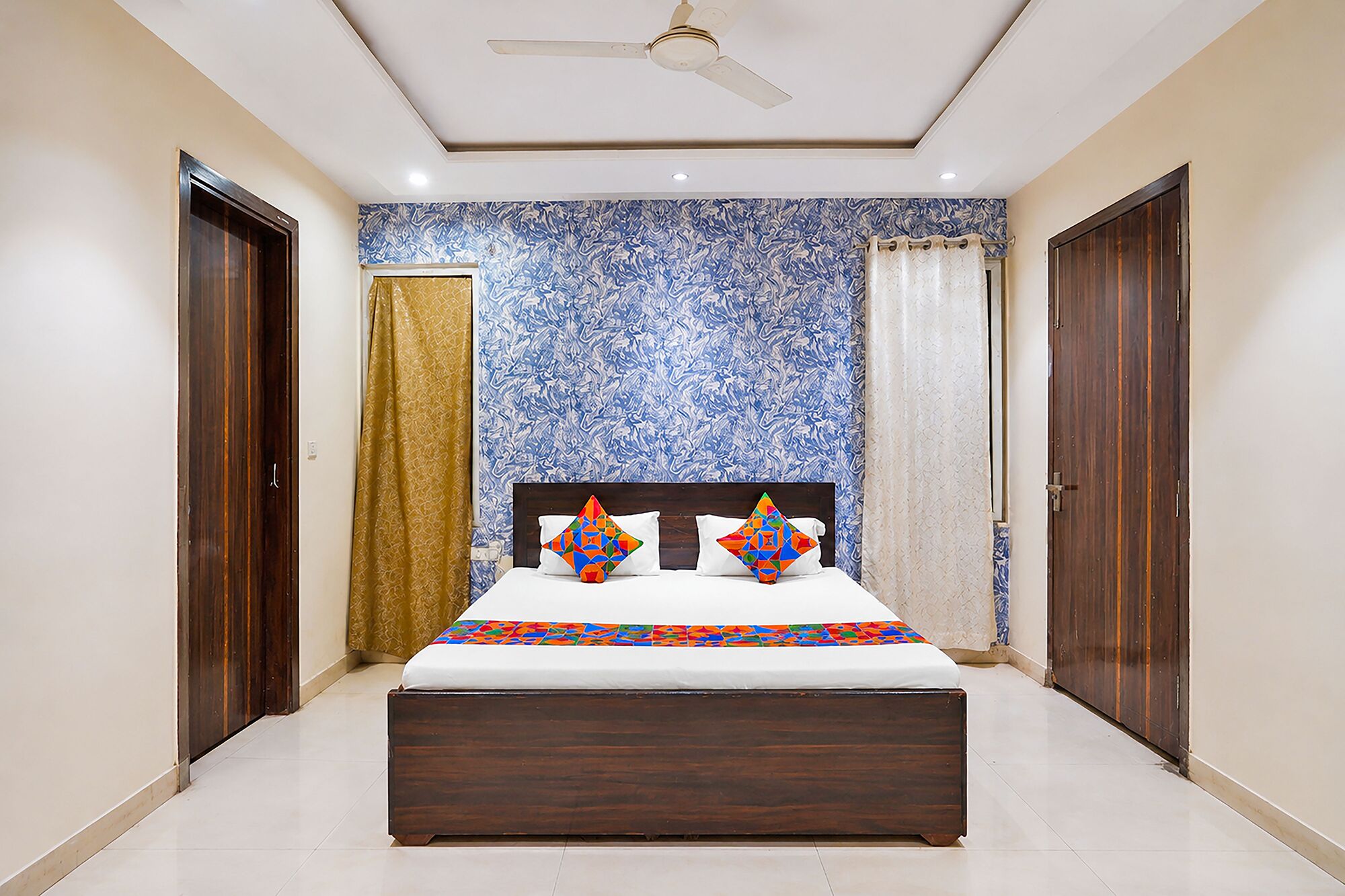 A bedroom with a bed, a ceiling fan, and patterned wallpaper.