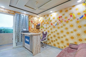 A reception area with a desk labeled 'Via,' a chair, and a patterned wall. - Via Amazing Guest House (New Delhi)
