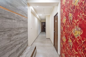 Un pasillo con una pared de mármol, una pared con diseño floral rojo y una puerta con el número 105.