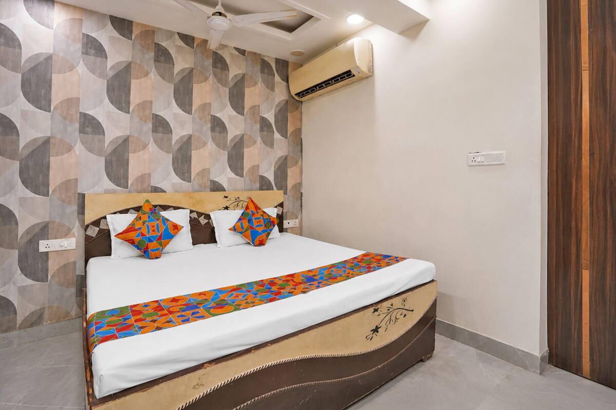 A bed with a patterned bedspread, a headboard with geometric designs, and a wall with circular patterns.